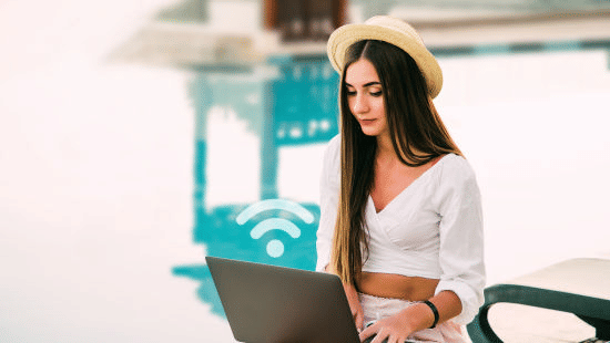 A girl working on her laptop by the pool.