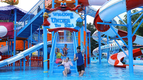 People enjoying a colourful Under the Sea themed water play area at Black Thunder with blue slides and a large splash pool.