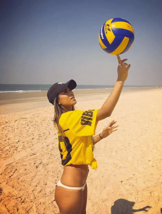 a woman on a beach spinning a volleybal on her finger - Caravela Beach Resort Goa