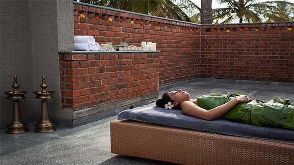 A person lying on a bed outdoors, brick wall background - Shreyas Retreat