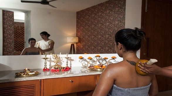 A client receiving a soothing herbal oil massage in a serene spa setting - Shreyas Retreat