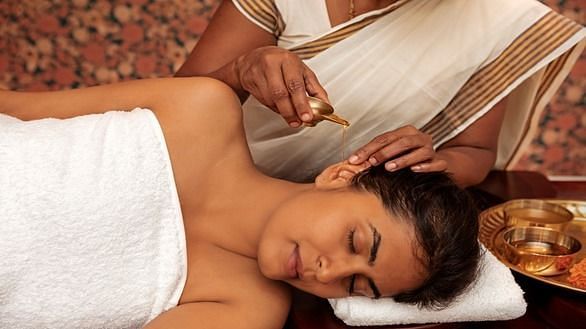 A close-up of a person receiving a head massage, white cloth, spa setting - Shreyas Retreat