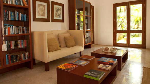 A library with a couch, bookshelves, and artwork, indoor setting - Shreyas Retreat