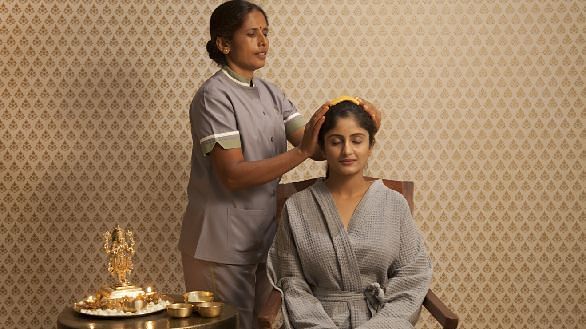 Two people in robes, one seated, indoor setting, spa treatment - Shreyas Retreat