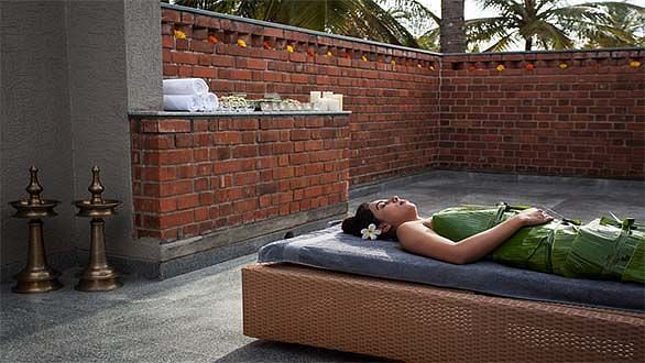 A person lying on a bed outdoors, brick wall background - Shreyas Retreat