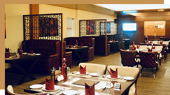 A spacious, well-lit Urban BBQ restaurant with neatly arranged tables, napkins, cushioned chairs, booth seating, and decorative screens dividing the dining area