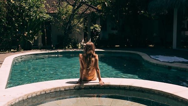 An image of a women sitting in front of a swimming pool.