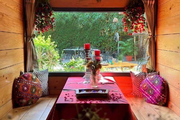 Indoor wooden dining nook with red tablecloth and cushions, set for two, at Karma Chalets.