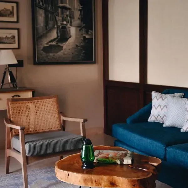 Lounge area with wooden armchairs, a blue sofa, framed photographs, and a round table at Karma Chalets.