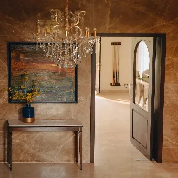 Interior hallway with a chandelier, wooden console table, artwork, and arched doorways at Karma Chalets.