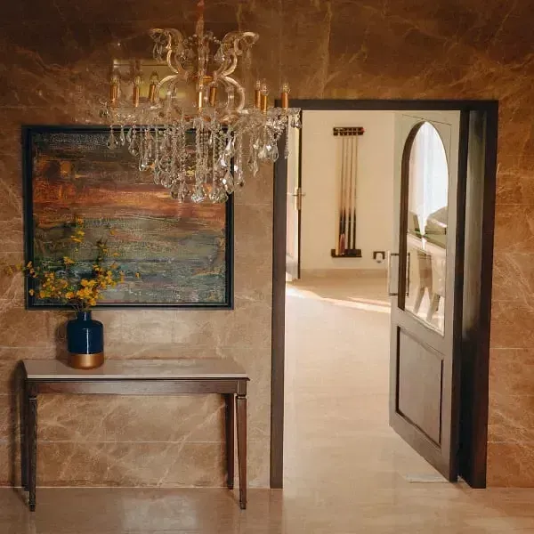 Interior hallway with a chandelier, wooden console table, artwork, and arched doorways at Karma Chalets.