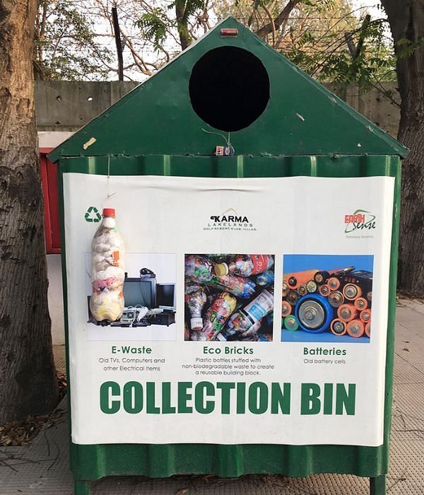 Green donation collection bin with posters and instructions displayed on the front at Karma Chalets.