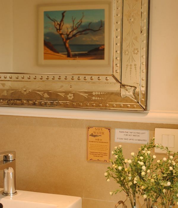 Sink area in a bathroom with a framed painting above and flower vase on the counter at Karma Chalets.