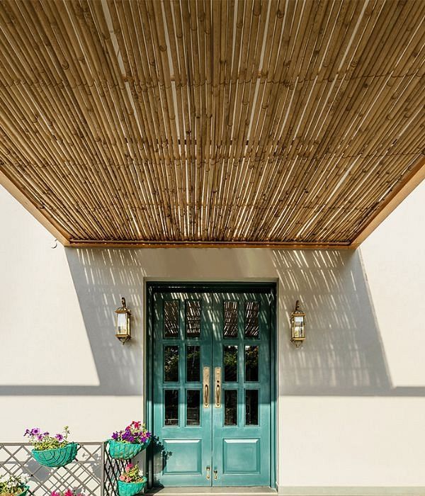 Entrance to a building with a green door and bamboo ceiling above at Karma Chalets.