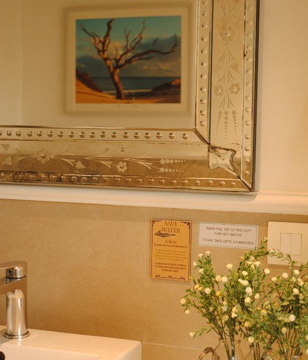Sink area in a bathroom with a framed painting above and flower vase on the counter at Karma Chalets.