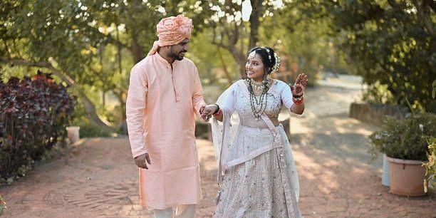 Elderly couple walking together in traditional Indian outfits, smiling and enjoying a garden setting.