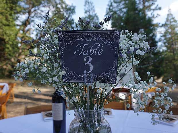 A board which says table 3 placed on a table alongside a bottle of wine - Shaver Lake Village Hotel.