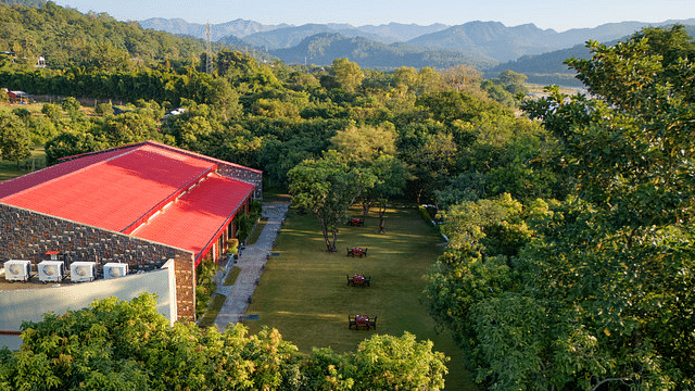 Resort building nestled in lush greenery with a mountain backdrop.