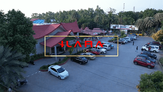 Elevated view of a parking area filled with cars in front of a red-roofed building, surrounded by trees at Ilara Hotels & Spa.