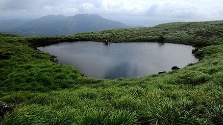 Serene lake nestled among lush green mountains and hills.