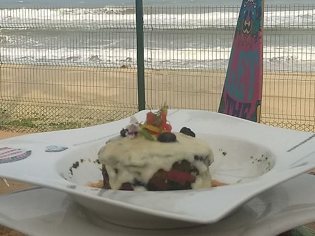 An image of a dish served on a plate with the backdrop of a sea shore