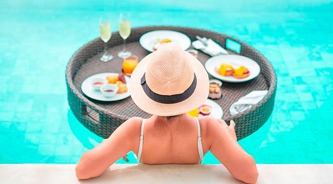A woman in a swimming pool with a breakfast platter at Nirvana Luxury Hotel, Ludhiana.