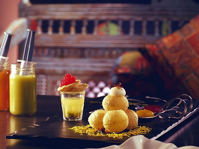 Traditional Indian desserts including gulab jamun and mango shake, served on a decorated table.