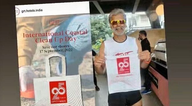 A person showing 25 years of GRTness bag in his hands standing beside a poster.