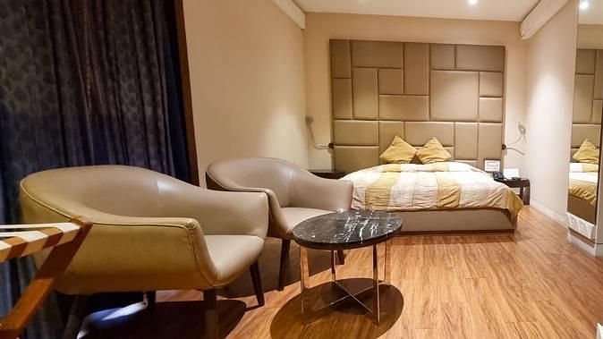 Room at Hotel Diplomat featuring a plush bed with a fancy headboard and sitting space with couch and coffee table under warm lighting