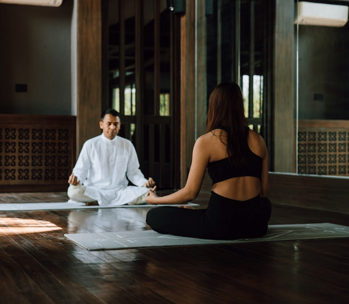 Two people practicing meditation in a quiet room which has natural light | Kavya Resort and Spa, Nagark