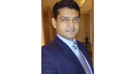 A man in a formal suit posing for a profile photo with text beside him - Lords Hotels & Resorts