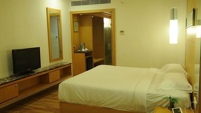 A modern hotel room with a neatly made bed, flat-screen TV, and soft lighting, ensuring a comfortable stay.- Dhanalakshmi Srinivasan Hotels, Perambalur