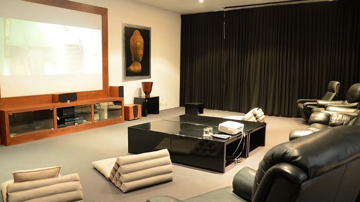 A modern home theatre with a large screen, dark drapes, and a minimalist design - Shreyas Retreat