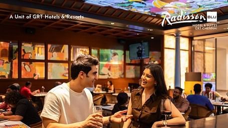 Creative dining scene photography of a young couple sharing drinks and appetizers in a vibrant hotel restaurant with colorful artwork and ambient lighting, enjoying the dining experience during their Independence Day special stay.