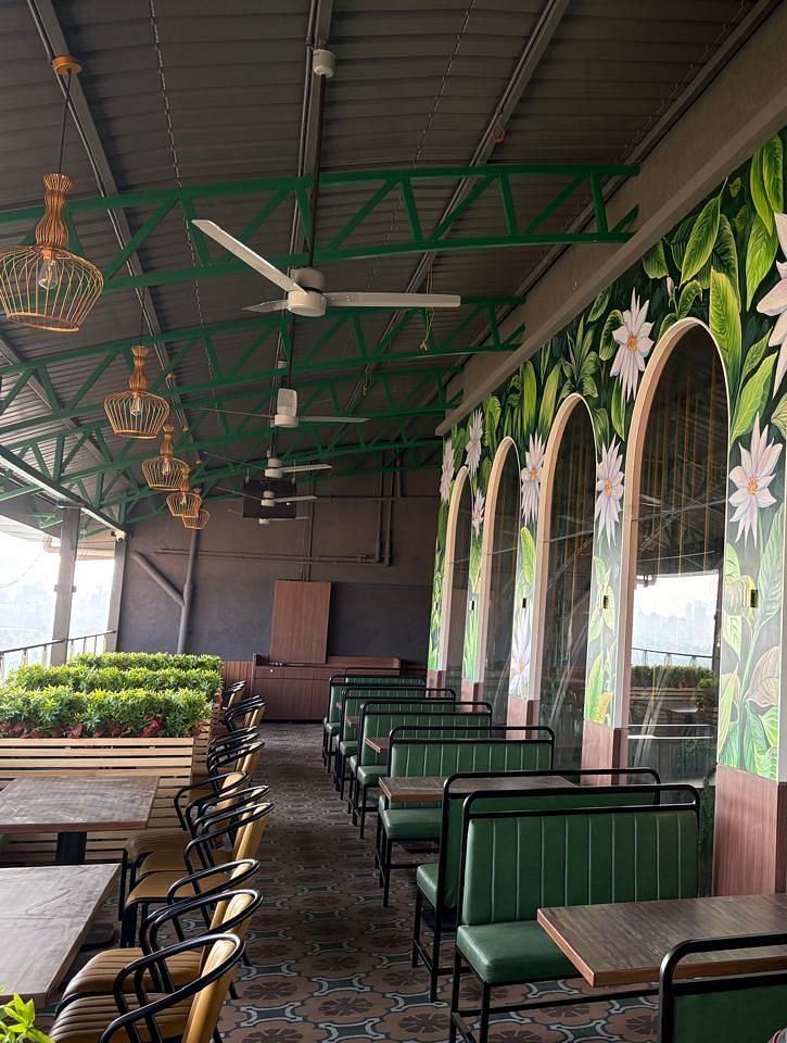 A dining area with green booth seating and large arched windows featuring decorative murals - Melior Inn