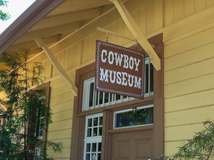 A sign reading Cowboy Museum hung outside a window - The Groveland Hotel.
