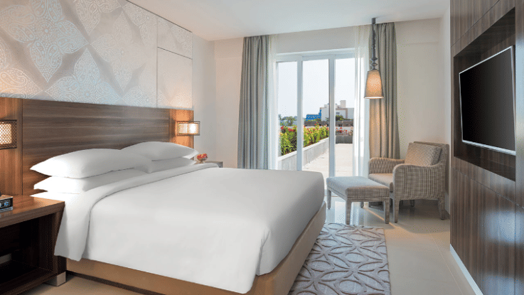 King Room with a balcony decked with a plush bed, couch and television at The Residency Towers Rameswaram