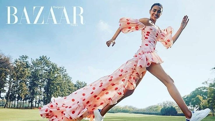 A cover page of Bazaar magazine of a women jumping on the lawn area - Karma Lakelands.