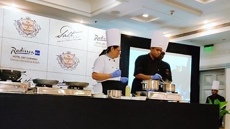 Chefs conducting a live cooking demonstration at an event.