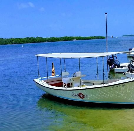 Boats moored on the shore at Casa Morada with clear skies, palm trees, and calm sea in the background.