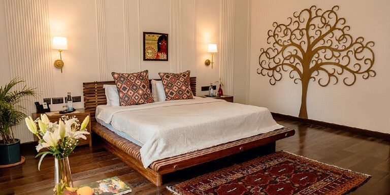 Bedroom with a double bed, decorative wall art, red rug, and bedside lighting at Karma Chalets.