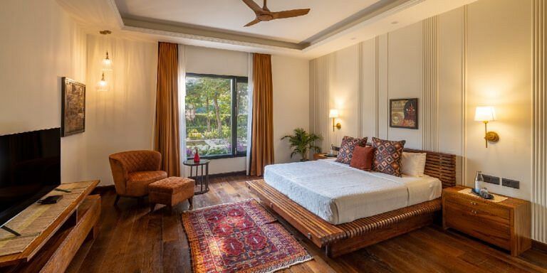 Bedroom with a white bed, wooden floors, and a seating area near a window at Karma Chalets.