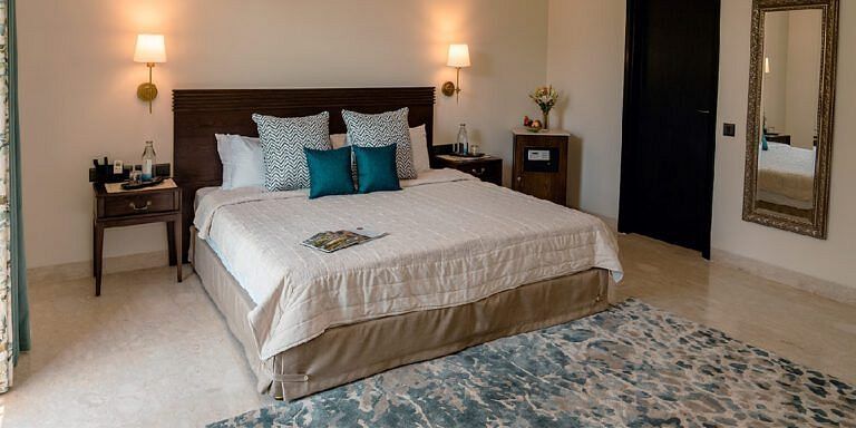 Bedroom with a double bed, bedside tables, lamps, and a blue rug at Karma Chalets.