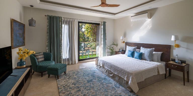 Bright bedroom with a double bed, armchairs, and natural light from large windows at Karma Chalets.