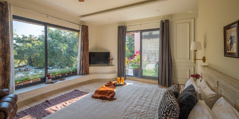 Bedroom with a large bed and a wide window opening to a green outdoor view at Karma Chalets.