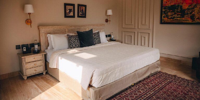 Bedroom with a beige bed, side tables, lamps, and a patterned red rug at Karma Chalets.