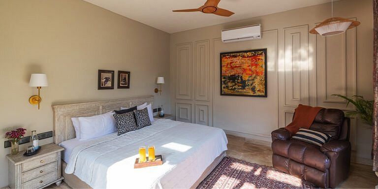 Bedroom with a white bed, wooden furniture, ceiling fan, and a painting on the wall at Karma Chalets.