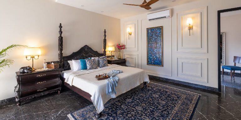 Bedroom with a carved wooden bed frame, dark furnishings, and a patterned rug at Karma Chalets.