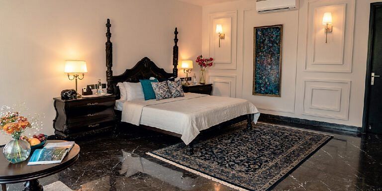 Bedroom with a four-poster bed, teal cushions, and classic wall detailing at Karma Chalets.