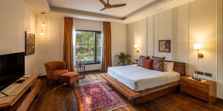 Bedroom with a white bed, wooden floors, and a seating area near a window at Karma Chalets.